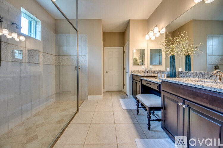 A bathroom with a glass shower stall and a vanity with a mirror.