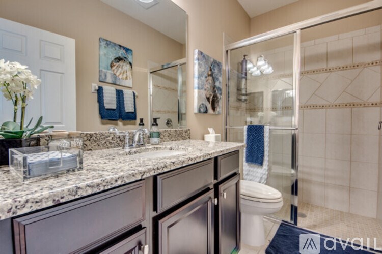 A bathroom with a marble countertop and a glass shower door.