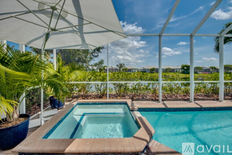 A pool surrounded by a white fence and palm trees.