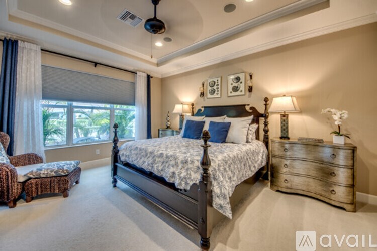 A bedroom with a large bed, a chair, and a window with blinds.