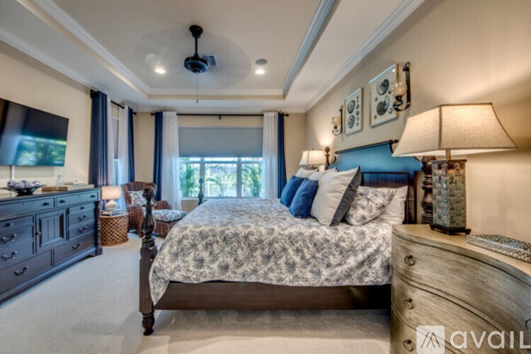 A bedroom with a large bed, a dresser, and a ceiling fan.