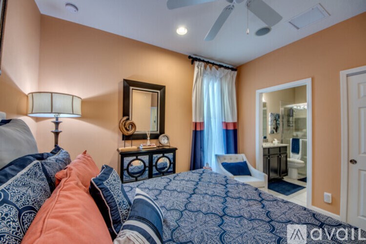 A bedroom with a bed, a dresser, a mirror, and a ceiling fan.