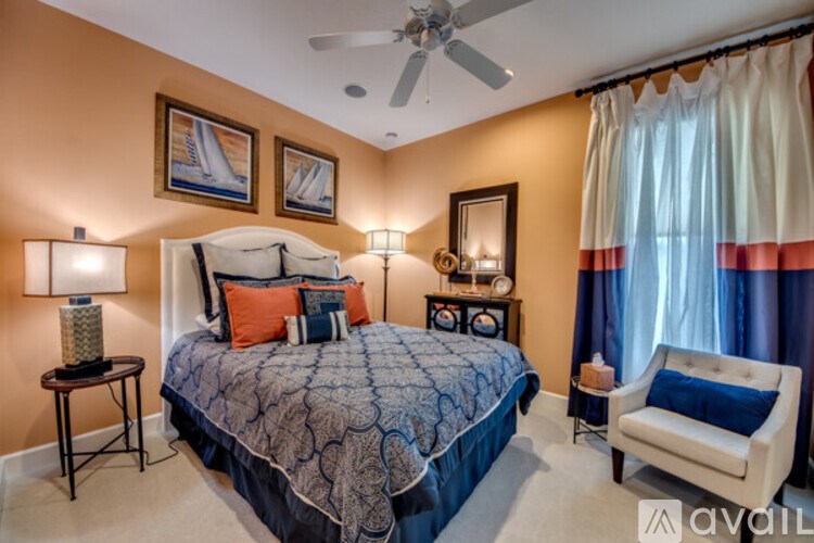 A bedroom with a large bed, a chair, and a ceiling fan.