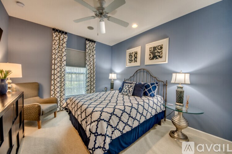 A bedroom with a bed, chair, and ceiling fan.