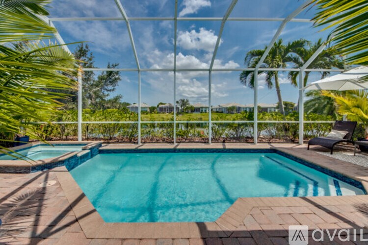 A pool surrounded by a white fence and palm trees.
