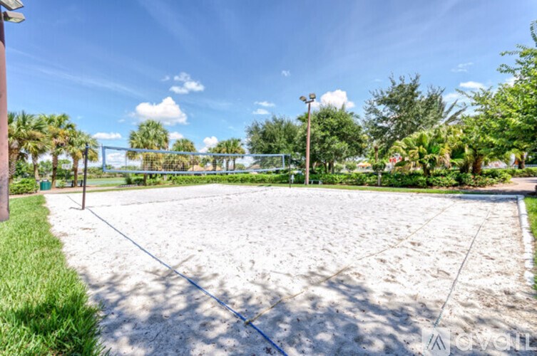 A sand volleyball court with a blue sky and clouds in the background.