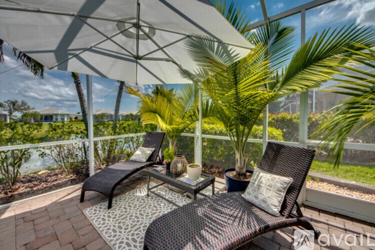 A patio with two chairs and a table under a white umbrella.