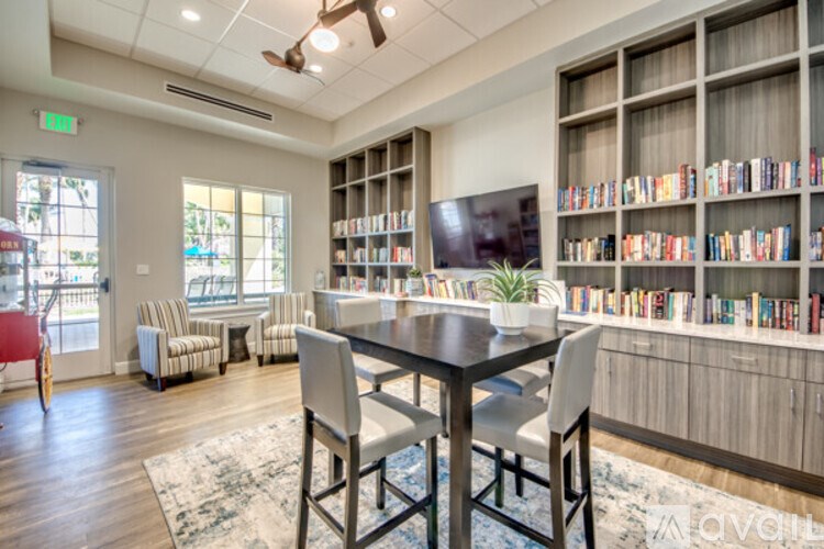 A room with a table, chairs, and a bookshelf filled with books.