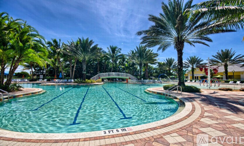 A swimming pool surrounded by palm trees and a clear blue sky.
