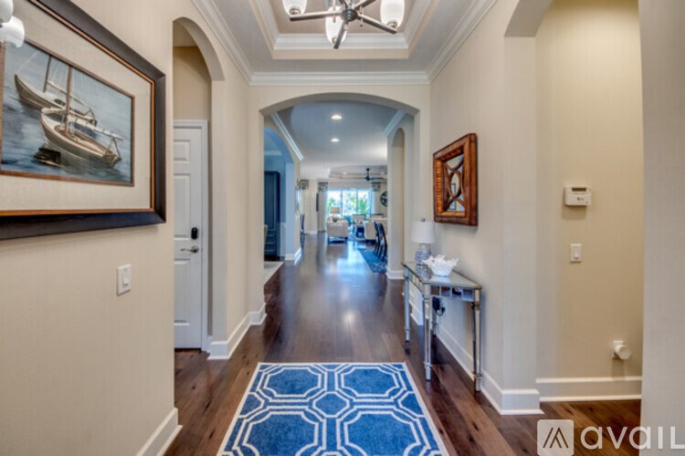 A hallway with a blue rug and a painting of a boat on the wall.