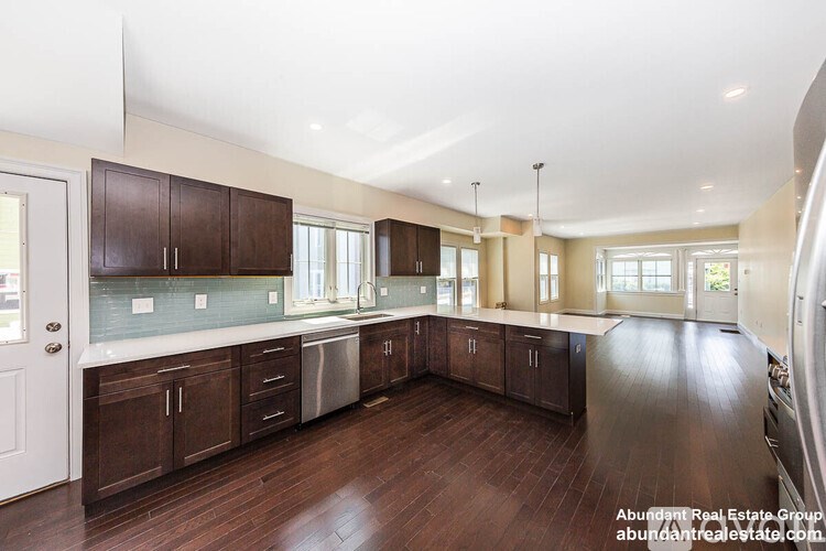 A spacious kitchen with dark wood cabinets and a white door.