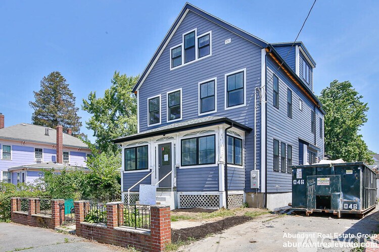 A blue house with a white fence and a green lawn.