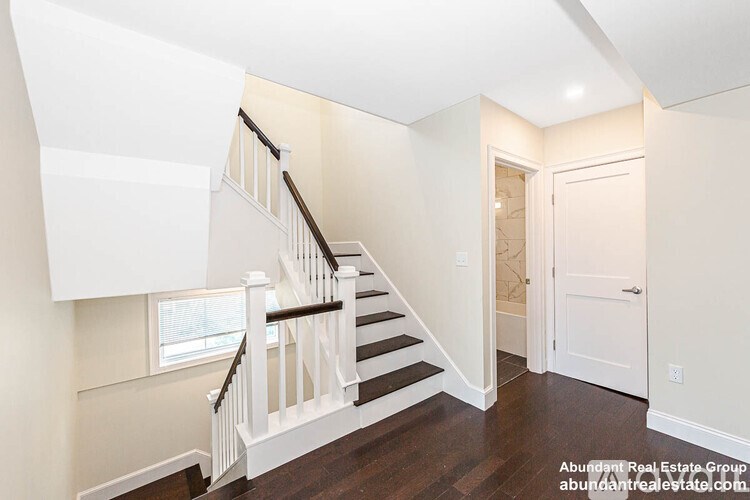 A staircase with a white railing and wooden steps leads to a door.