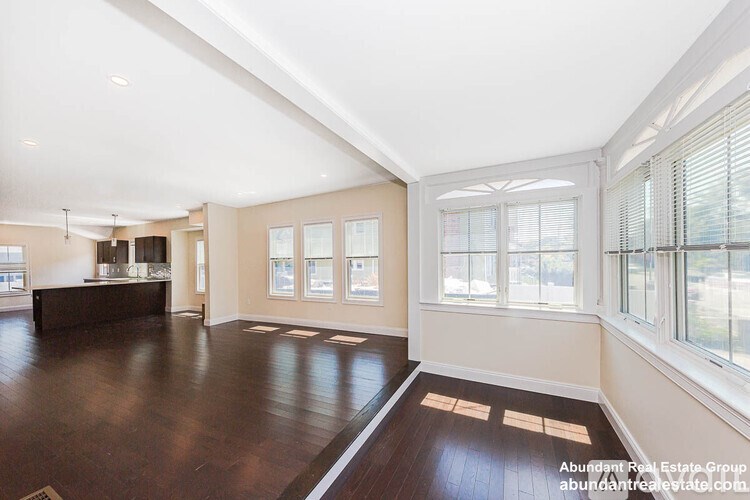 A spacious room with wooden floors and large windows.