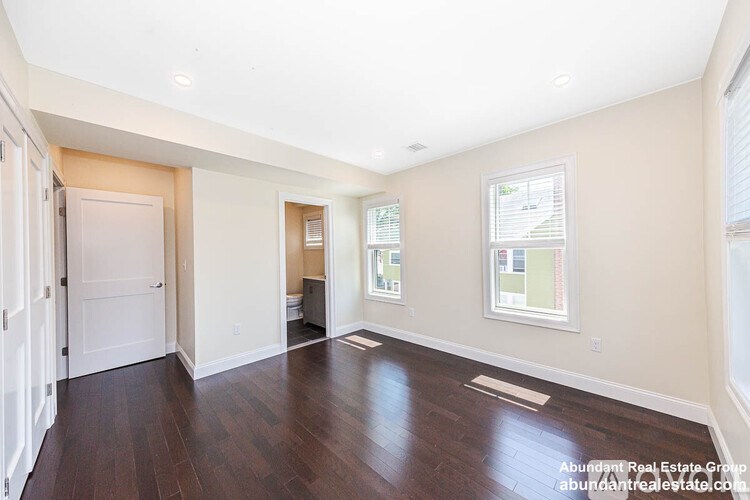 A spacious room with wood flooring and white walls.