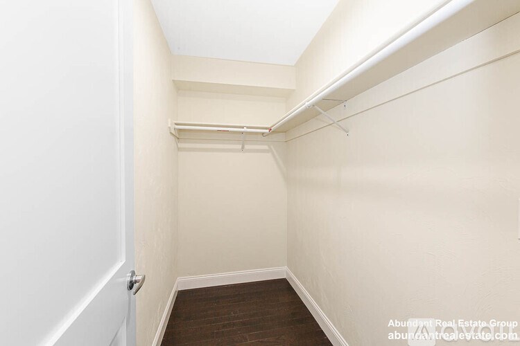 A small, empty room with a wooden floor and white walls.