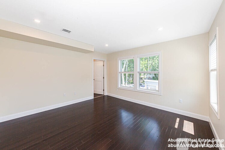A spacious room with wooden floors and a large window.