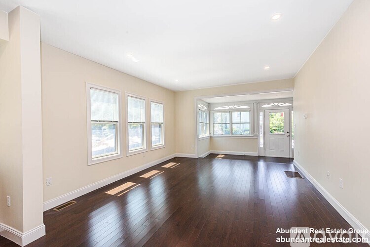 A spacious room with wooden floors and a large window.