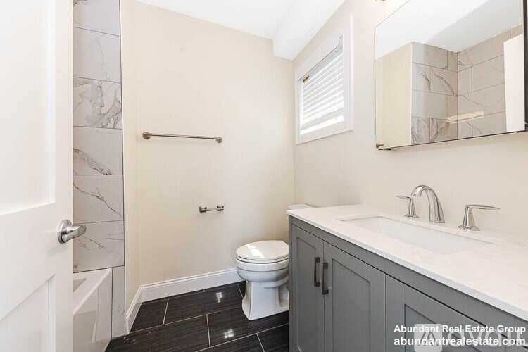 A white toilet sits in a bathroom with a marble tile floor.