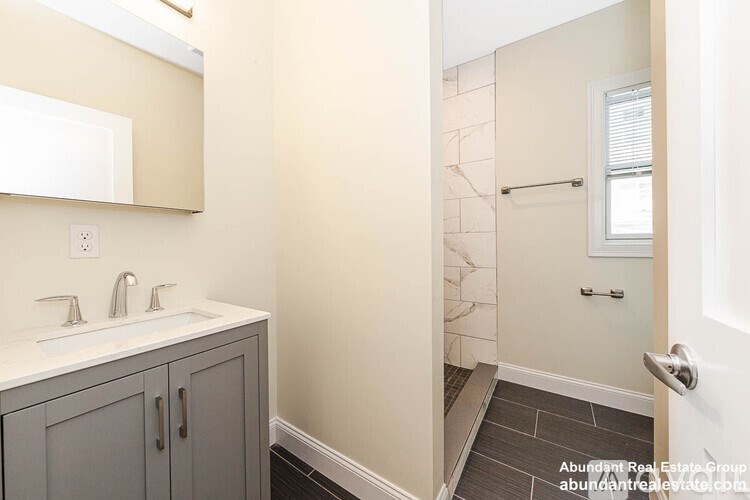 A bathroom with a white sink and grey cabinets.