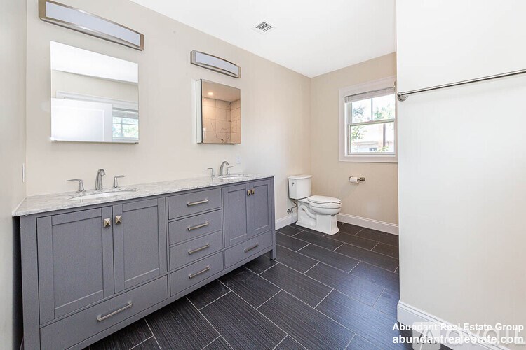 A bathroom with a toilet, sink, and vanity.