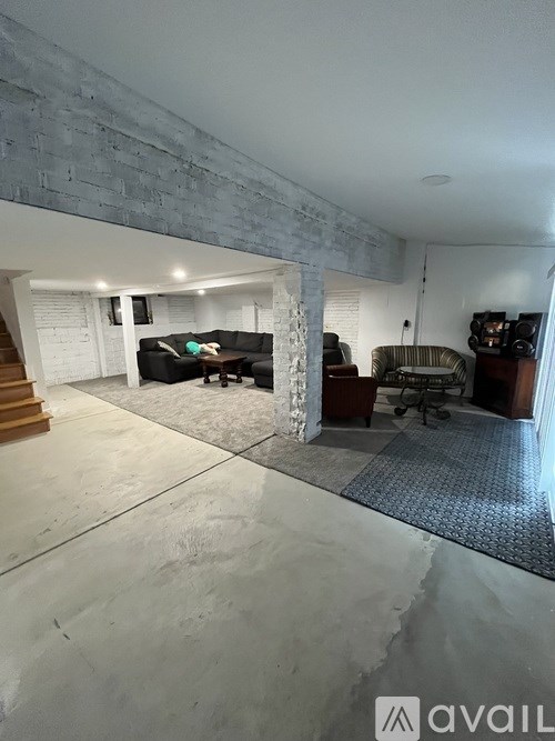 A living room with a couch, chairs, and a television.