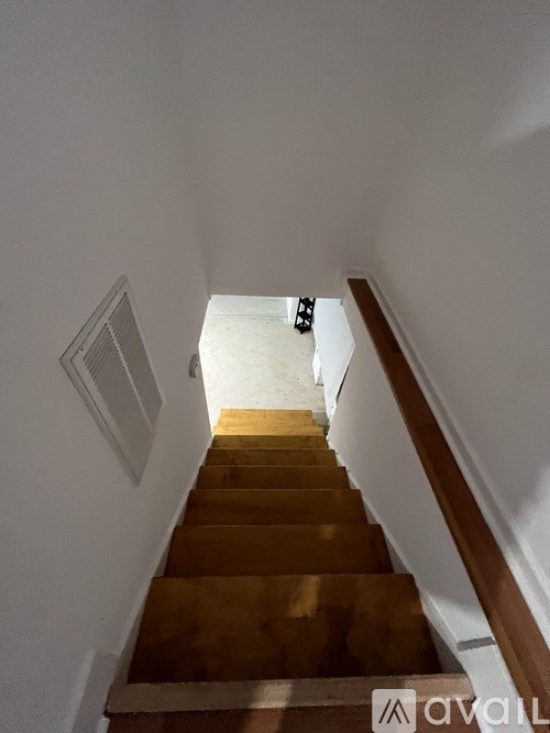 A staircase with wooden steps and a white wall on the side.