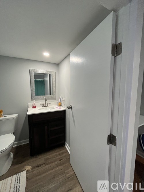 A bathroom with a white toilet, a sink with a mirror above it, and a white door.