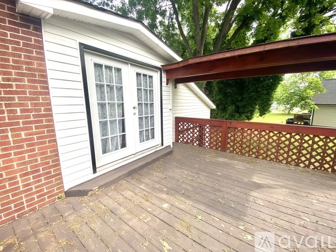 A white door with a black frame is on a wooden deck.