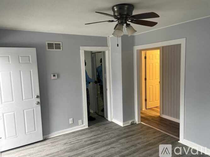 A room with a ceiling fan and a person standing in the doorway.