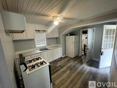 A kitchen with a stove, cabinets, and a window.