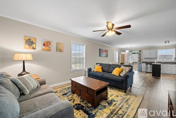A living room with a grey couch, a coffee table, and a ceiling fan.