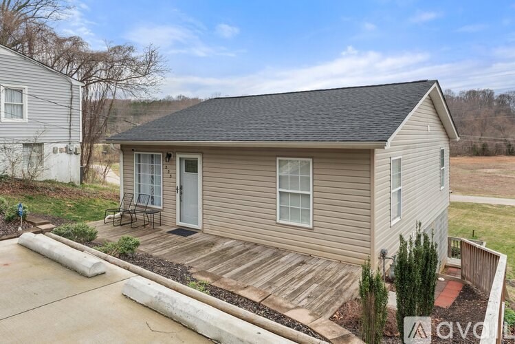 A small house with a grey roof and a wooden deck.