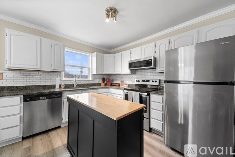 A kitchen with a wooden island and stainless steel appliances.