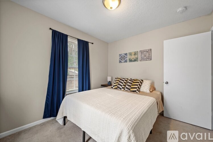 A bedroom with a bed, pillows, and pictures on the wall.