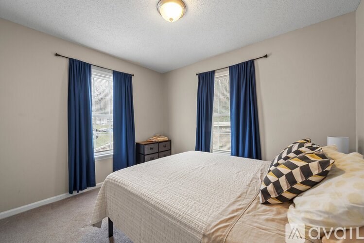 A bedroom with a bed, nightstands, and a window with blue curtains.