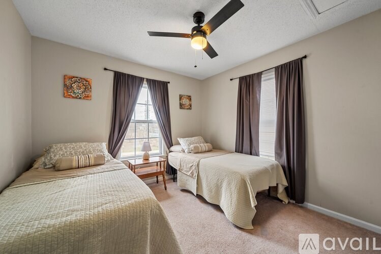 A bedroom with two beds and a ceiling fan.