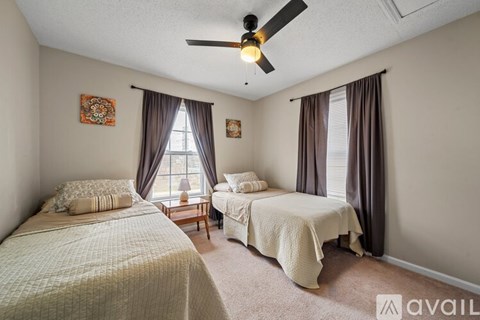 A bedroom with two beds and a ceiling fan.