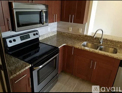 A kitchen with a black stove top oven and a microwave above it.
