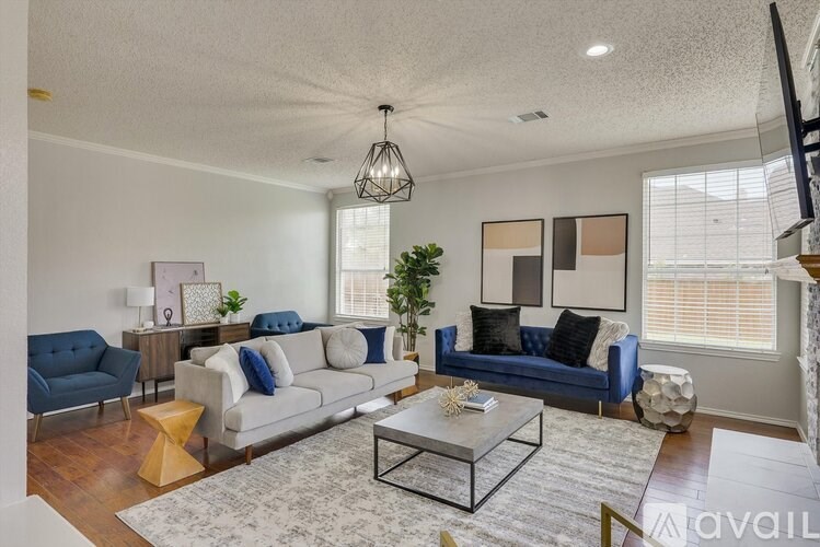 A living room with a blue couch, a grey couch, a coffee table, and a hanging light fixture.