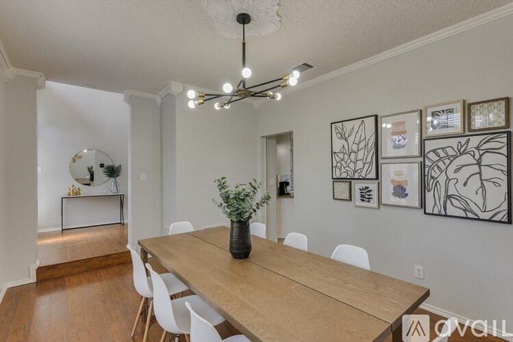 A dining room with a wooden table and white chairs.