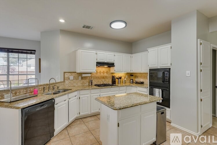 A kitchen with granite countertops and white cabinets.