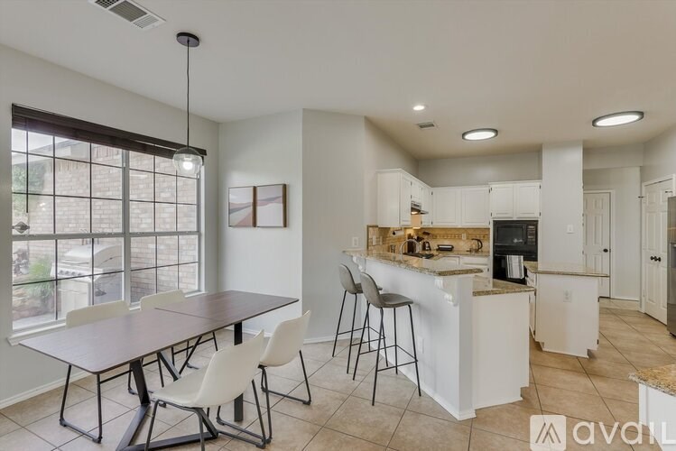 A kitchen with a table and chairs in front of a window.