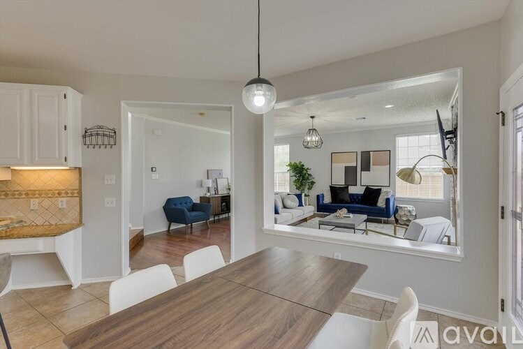 A modern dining room with a wooden table and white chairs.