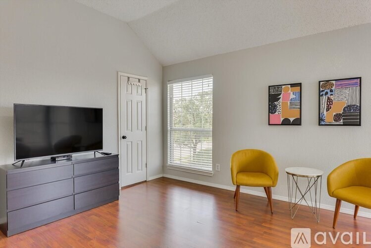 A living room with a television, two chairs, and two paintings on the wall.