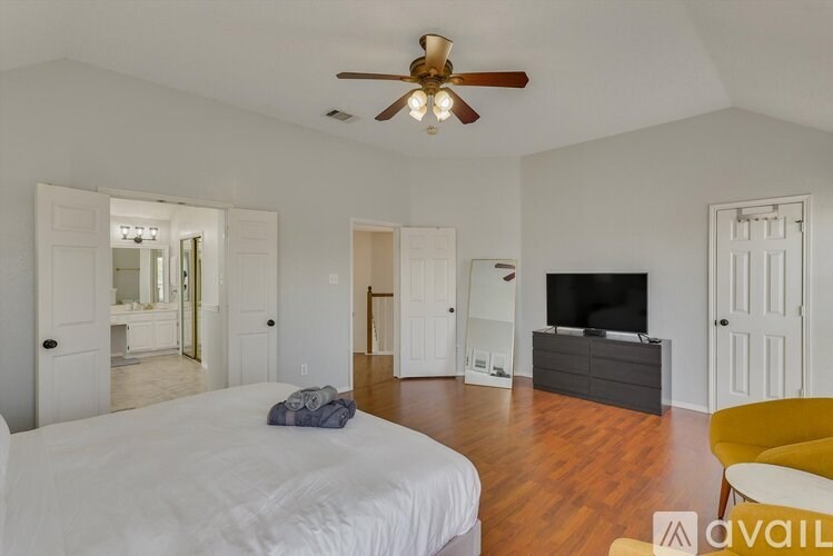 A bedroom with a bed, a television, and a yellow chair.