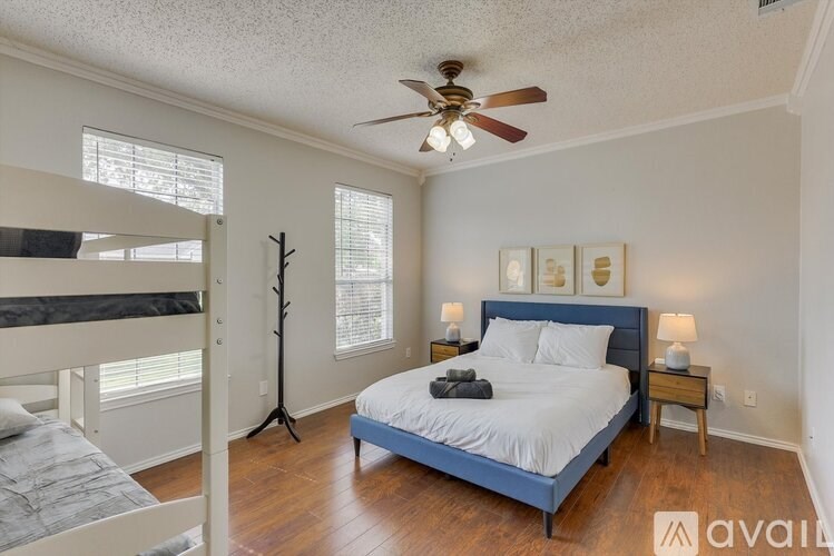 A bedroom with a bed, a bunk bed, and a ceiling fan.