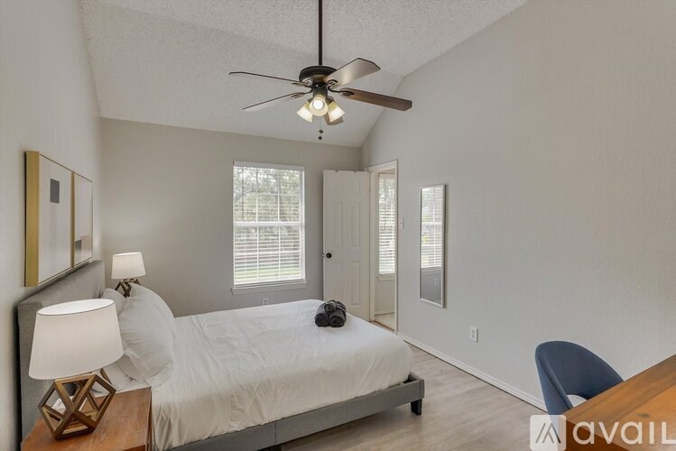 A bedroom with a bed, a ceiling fan, and a chair.