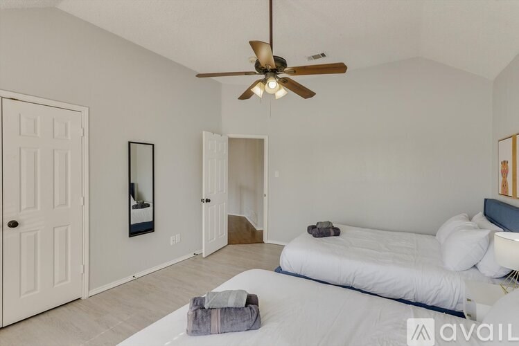 A bedroom with a bed, a ceiling fan, and a mirror.