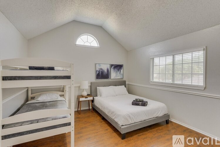 A bedroom with a white bed and a window with blinds.